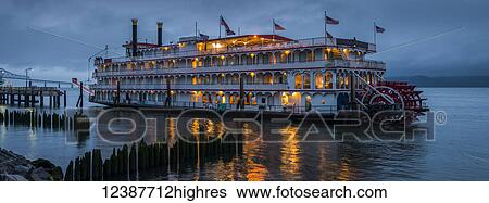 Stock Photograph - Lights illuminating a river boat docked on the Columbia River at dusk; Astoria, Oregon, United States of America. Fotosearch