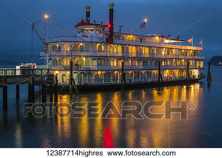 Stock Photograph - Lights illuminating a river boat docked on the Columbia River at dusk; Astoria, Oregon, United States of America. Fotosearch