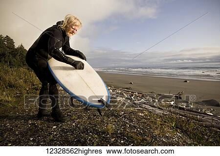 Stock Photograph - Local surfer from Homer Alaska, 'The Iceman', Don MacNamara, waxing his board, Southeast Alaska; Yakutat, Alaska, United States of America. Fotosearch