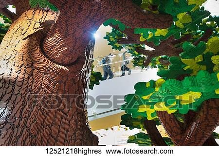 Stock Photograph - Looking through giant Lego tree to mother and daughter climbing stairs of the Lego House; Billund, Denmark. Fotosearch