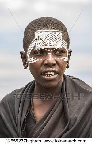 Stock Photograph - Maasai youth with traditional face paint signifying that he has completed the initiation process for entering adulthood the Ngorongoro Conservation Area; Tanzania. Fotosearch