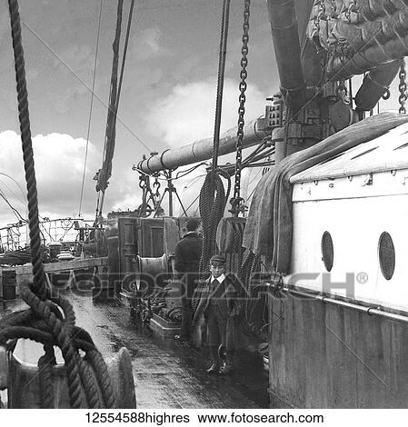 Stock Photograph - Magic lantern slide circa 1880, Victorian/Edwardian Social History. A black and white image of a boy and man on board a whaling (whaler) ship.. Fotosearch