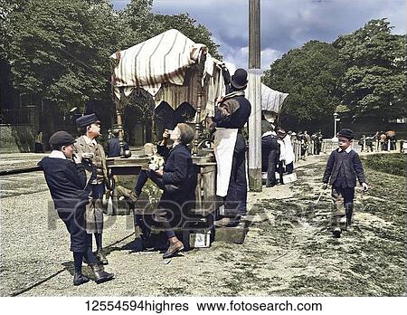 Stock Photograph - Magic lantern slide circa 1880, Victorian/Edwardian Social History. A view of children and people at a market in the park, perhaps an exhibition. The childen are eating sweets and treats.. Fotosearch