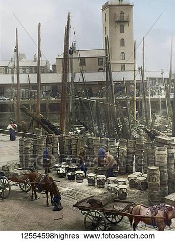 Stock Photograph - Magic Lantern Slide circa 1880, Victorian/Edwardian Social History. A view of North Shields Fish Quay market with fishing boats, herring, barrels and fishermen; North Shields, Tyne and Wear, England. Fotosearch