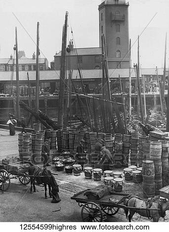 Stock Photograph - Magic Lantern Slide circa 1880, Victorian/Edwardian Social History. A view of North Shields Fish Quay market with fishing boats, herring, barrels and fishermen; North Shields, Tyne and Wear, England. Fotosearch