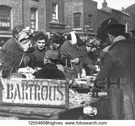 Stock Photograph - Magic lantern slide circa 1880, Victorian/Edwardian Social History. A fishmonger stall in the market with lots of people buying fish, including children and a lady with a bandage on her chin, perhaps from dental work.. Fotosearch