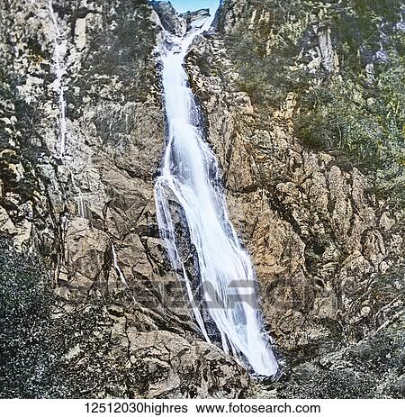 Stock Photograph - Magic Lantern slide circa 1900 hand coloured. created in 1887. A tour of North Wales. 21 Aber Waterfall. A visit to this beautiful cascade may be made the basis of a mornings excursion. It is situated about two miles beyond the little village of Aber,.... Fotosearch