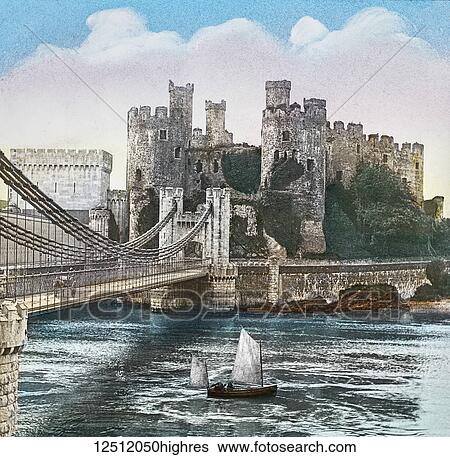 Stock Photograph - Magic Lantern slide circa 1900 hand coloured. created in 1887. A tour of North Wales. 4 Conway Castle and Bridges. Here, before crossing the river, we have a fine view of the Suspension Bridge, designed by Telford, which is fastened by chains to the.... Fotosearch