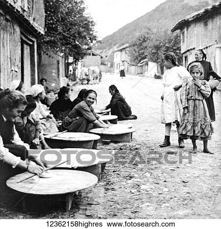 Stock Photograph - Magic lantern slide circa 1900. VictorianMaking native bread in the streets of Berkovites, Bulgaria. Ladies ion the street rolling bread ready for cooking. Children looking on. Fotosearch