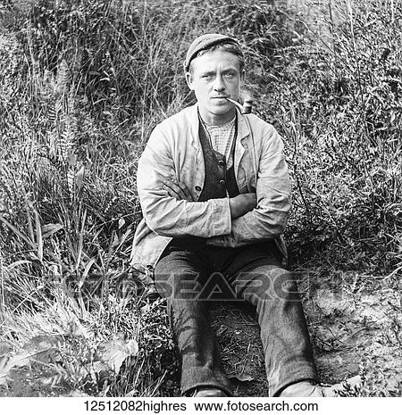 Stock Photograph - Magic lantern slide circa 1900. Victorian. Social History. Victorian farm labourer having a break smoking his pipe. Fotosearch