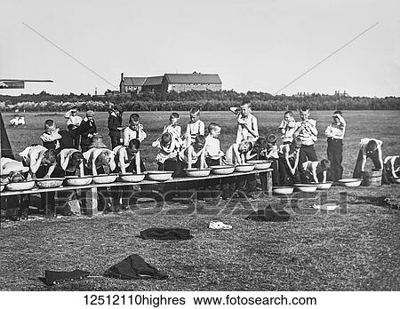 Stock Photograph - Magic lantern slide circa 1900. Victorian. Social History. Orphans in a field washing in tin wash basins,. Fotosearch