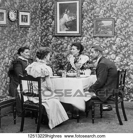 Stock Photograph - Magic lantern slide circa 1900. Victorian. Social History. Image from a slide presentation entitled In His step or In jesus Name. A victorian tea in t he front room of a house.. Fotosearch