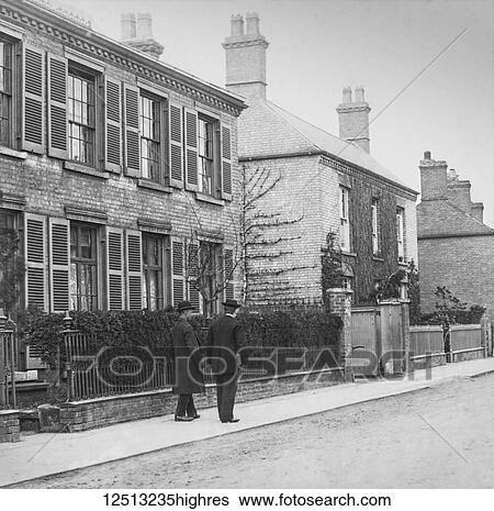 Stock Photograph - Magic lantern slide circa 1900. Victorian. Social History. Image from a slide presentation entitled In His step or In jesus Name. The minister with a member of the congregation walking in the street. Fotosearch