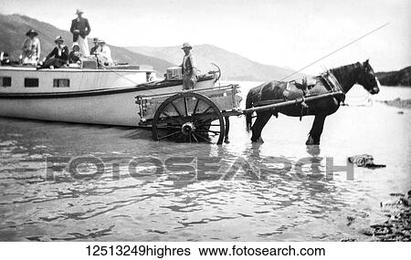 Stock Photograph - Magic lantern slide circa 1900. Victorian/Edwardian social history. A motorlaunch is replenished with Kalif motor spirit. The wooded crate contained 4 gallon containers of motor spirit. Supplies are brought to the boat by horse and cart. The family.... Fotosearch