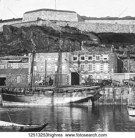 Stock Photograph - Magic lantern slide circa 1900. Victorian. Sailing boat and horse drawn carts at London Docks, Wheel barrows steam crane and iron foundery on banks of Thames. Fotosearch