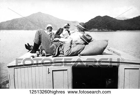 Stock Photograph - Magic lantern slide circa 1900. Victorian/Edwardian social history. Faily on the roof of a motor launch in New Zealand near Queenstown.. Fotosearch