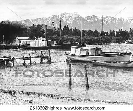 Stock Photograph - Magic lantern slide circa 1900. Victorian/Edwardian social history. Boats and pleasure paddle steamer at the warf in Queenstown, new Zealand. Fotosearch