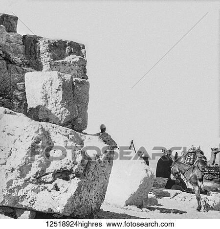 Stock Photograph - Magic lantern slide circa 1900. Victorian/Edwardian. Social History. At the foot of the pyramids with donkey, camel and locals. Fotosearch