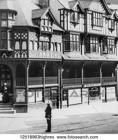 Stock Photograph - Magic lantern slide circa 1900. Victorian. Social History. Bridge Street Chester with policeman waeruing a white helmet. Various shops including bicyle shop named wheeleries a tea shoop named Ellis and Davies. Midiebval buildings. Fotosearch