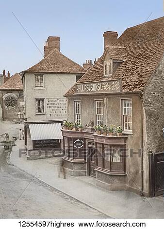 Stock Photograph - Magic lantern slide circa 1900, Victorian. Faringdon village street scene including the famous Cousell clock, various shops, a pub and people; Faringdon, Oxfordshire, England. Fotosearch