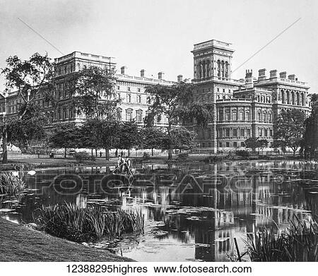 Stock Photograph - Magic Lantern slide circa 1900 views of London, England in Victorian times. Government buildings from St James Park with pond in front. Maintenance men cleaning the pond. Fotosearch