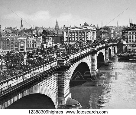 Stock Photograph - Magic Lantern slide circa 1900 views of London, England in Victorian times. London Bridge in Victorian rush hour. The bridge is full of people, horses, carriages, carts. Advertising boards for American Merchants, Daily Telegraph, Daily News, Pearl.... Fotosearch