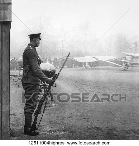 Stock Photograph - Magic lantern slide WW1, 1914-1918, World war one images. Soldier standing guard. Standing with a gun with Fokker aircraft and torpedoes in the background. Display of captured German weapons and artillary at Horse Guards Parade, London 3rd November 1915.. Fotosearch