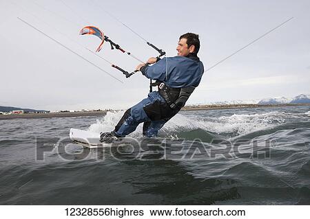 Stock Photograph - Man kitesurfing in Kachemak Bay, South-central Alaska; Homer, Alaska, United States of America. Fotosearch