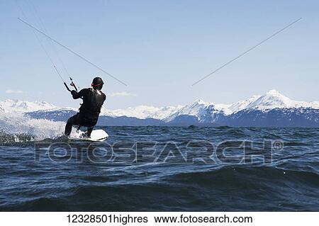 Man kitesurfing with Kenai Mountains in the background, South-central Alaska; Homer, Alaska, United States of America View Large Photo Image Stock Photograph - Man kitesurfing with Kenai Mountains in the background, South-central Alaska; Homer, Alaska, United States of America. Fotosearch