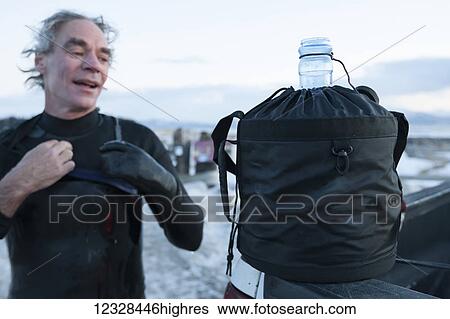 Stock Photograph - Man rinsing off after surfing in Kachemak Bay, South-central Alaska; Homer, Alaska, United States of America. Fotosearch