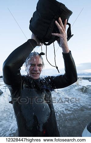 Stock Photograph - Man rinsing off after surfing in Kachemak Bay, South-central Alaska; Homer, Alaska, United States of America. Fotosearch
