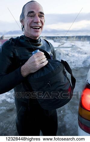 Stock Photograph - Man rinsing off after surfing in Kachemak Bay, South-central Alaska; Homer, Alaska, United States of America. Fotosearch