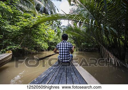 Man rowing a boat in a canal of the Mekong Delta; Long An, Vietnam View Large Photo Image Stock Photograph - Man rowing a boat in a canal of the Mekong Delta; Long An, Vietnam. Fotosearch