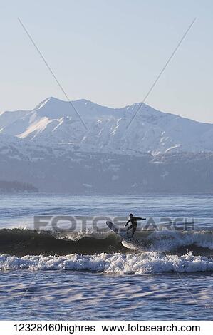 Stock Photograph - Man surfing in Kachemak Bay, South-central Alaska; Homer Spit, Alaska, United States of America. Fotosearch