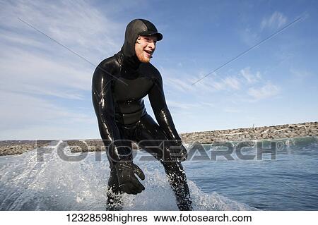 Stock Photograph - Man surfing with the beach in the background, South-central Alaska; Homer, Alaska, United States of America. Fotosearch