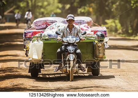 Stock Photograph - Man transporting garbage on a motorcycle; Sambor Prei Kuk, Kompong Thom, Cambodia. Fotosearch