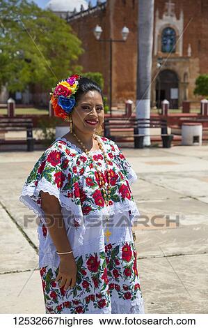 Stock Photograph - Mayan woman in traditional dress standing outside the Church of San Antonio de Padua, a former convent; Ticul, Yucatan, Mexico. Fotosearch