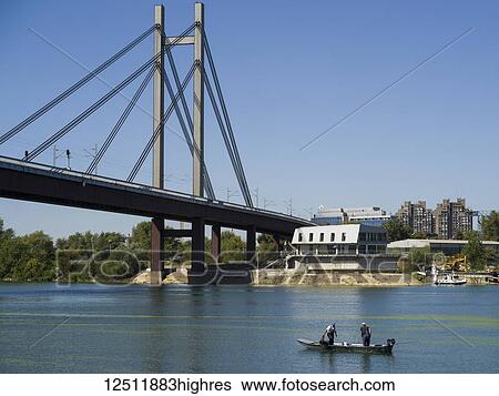 Men in a boat in the Sava River with a bridge crossing and blue sky; Belgrade, Vojvodina, Serbia View Large Photo Image Stock Photograph - Men in a boat in the Sava River with a bridge crossing and blue sky; Belgrade, Vojvodina, Serbia. Fotosearch