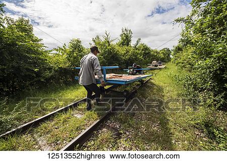 Men placing the bamboo platform on the wheels of the Norry, the bamboo train; Battambang, Cambodia View Large Photo Image Stock Photograph - Men placing the bamboo platform on the wheels of the Norry, the bamboo train; Battambang, Cambodia. Fotosearch