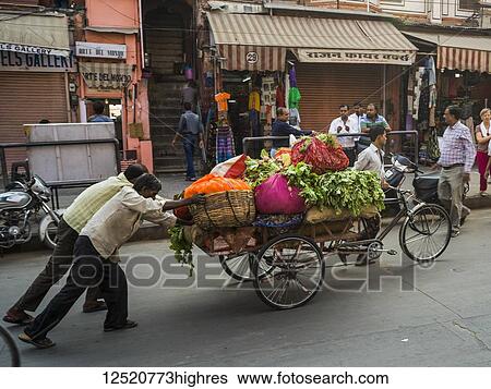 Stock Photograph - Men push a cart full of fresh produce down the street; Jaipur, Rajasthan, India. Fotosearch