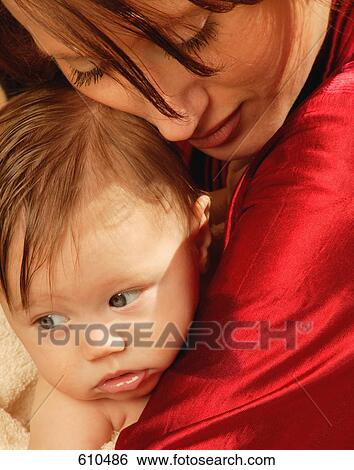 Stock Photograph - Mother holds baby in arms after bath time. Fotosearch
