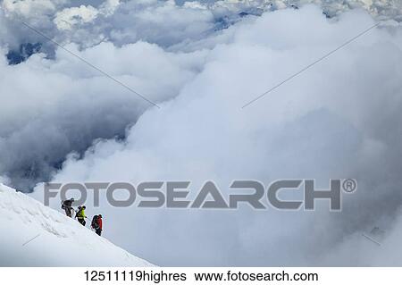 Stock Photograph - Mountain climbers departing Aiguille du midi into the clouds; Chamonix-Mont-Blanc, Haute-Savoie, France. Fotosearch