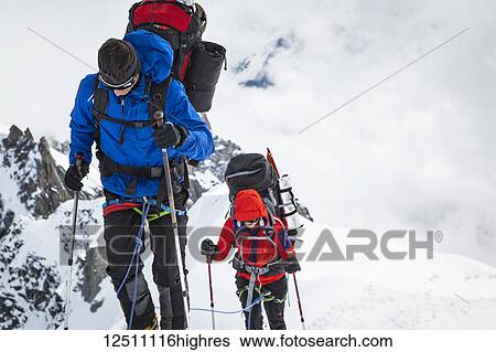 Stock Photograph - Mountain climbers with equipment on a snowy ridge, Aiguille du midi; Chamonix-Mont-Blanc, Haute-Savoie, France. Fotosearch