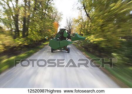 Stock Photograph - Moving farm equipment on a rural road to a soybean field during harvest; Minnesota, United States of America. Fotosearch