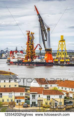 Stock Photograph - Offshore vessel in dock on the River Tyne with houses in the foreground; North Shields, Tyne and Wear, England. Fotosearch