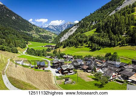 Stock Photograph - Overlooking the village of Issert surrounded by Swiss Alps under blue sky; Issert, Val Ferret, Switzerland. Fotosearch