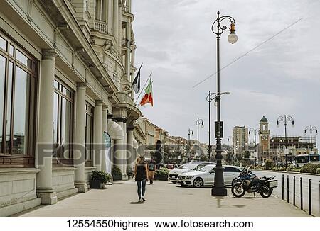 Stock Photograph - Pedestrians walk past historic architecture along a street; Italy. Fotosearch