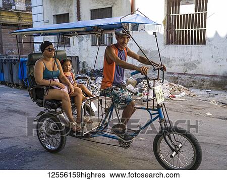 Stock Photograph - Pedicab with another and daughter on the streets of Havana; Havana, Cuba. Fotosearch