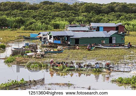 Stock Photograph - People in a public boat by a floating village in the Tonle Sap; Siem Reap, Cambodia. Fotosearch
