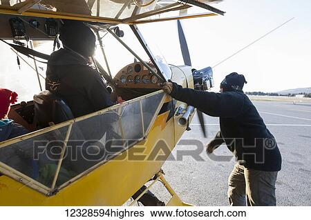 Stock Photograph - People preparing a flight in a Piper J-3 Cub; Alaska, United States of America. Fotosearch